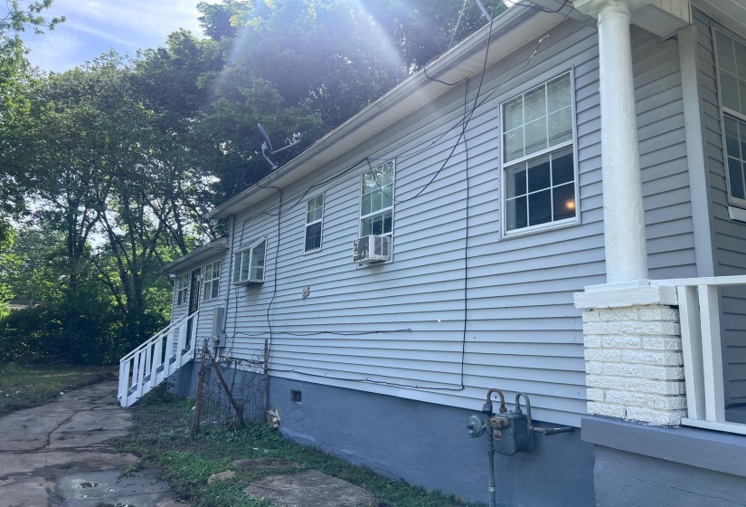Light grey siding exterior with white trim windows and a white painted porch column with a brick base