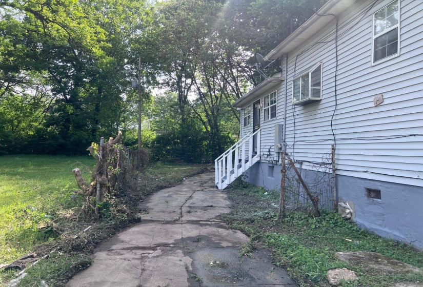 Siding exterior featuring a white painted staircase and a partial concrete pathway