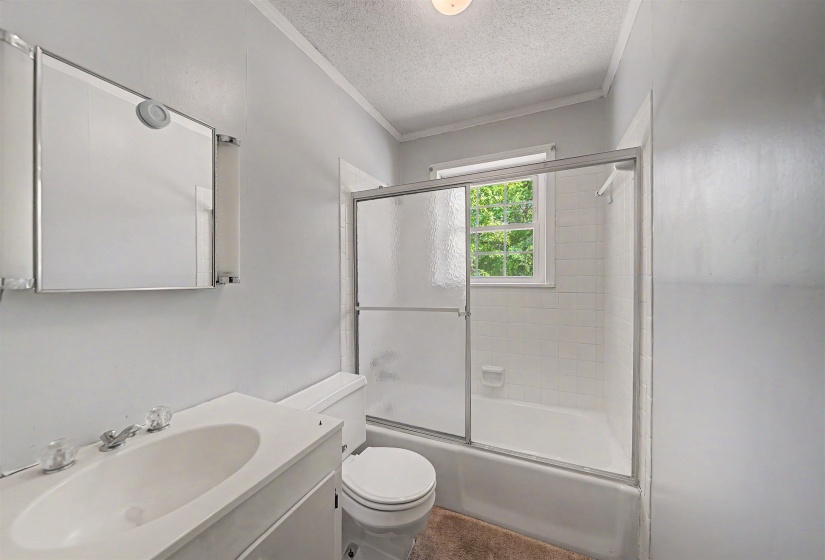 Full bathroom featuring a vanity with integrated sink, mirrored medicine cabinet with integrated lighting, and a tub/shower combination with sliding glass enclosure