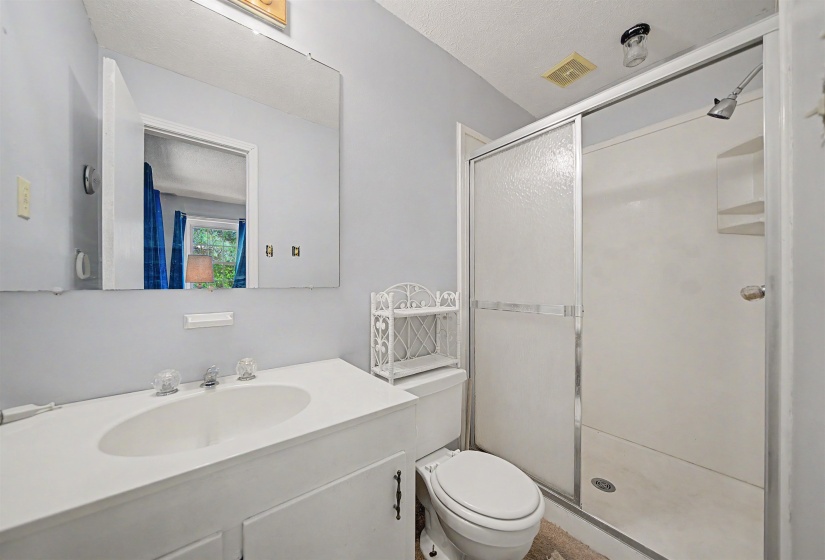 Full bathroom featuring a single vanity, frameless mirror, and a shower with a sliding glass door