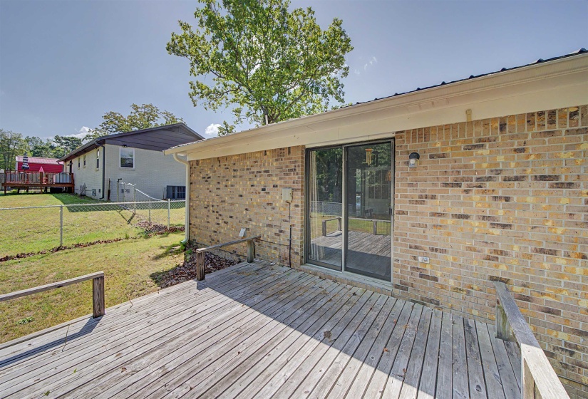 Wood deck extending from the brick exterior, featuring sliding glass doors and a wall-mounted light fixture