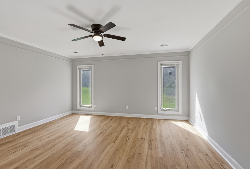 Spacious room featuring wood-finish flooring, light grey walls, and white crown molding