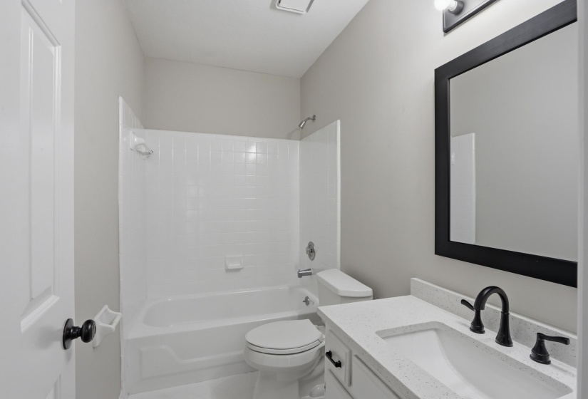 Bathroom featuring a white vanity with a light-colored countertop, an undermount sink, and dark-finished hardware