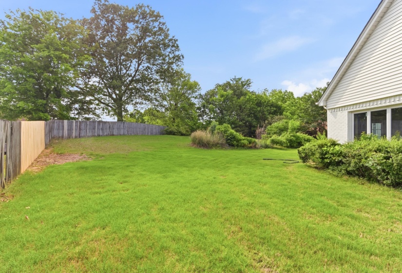 Expansive green lawn framed by a wooden fence and mature trees