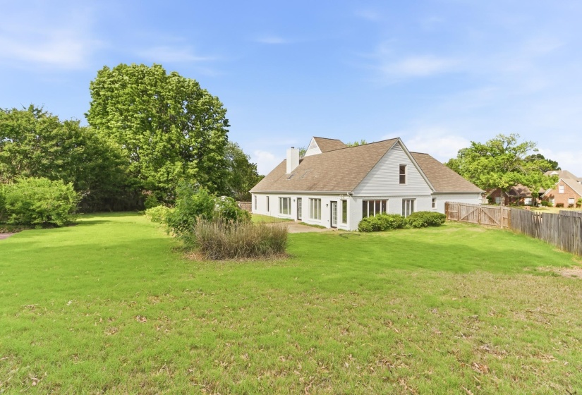 Expansive green lawn bordering the rear facade of a white-sided residence