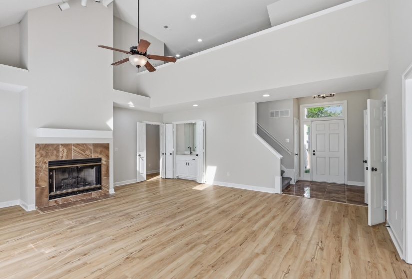 Spacious living area featuring wood-finish flooring, a tiled fireplace with a mantel, and a built-in wet bar with a sink and cabinetry