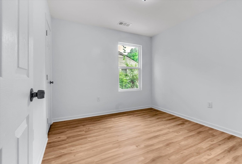 Light-filled room featuring wood-finish flooring, white baseboards, and a double-hung window