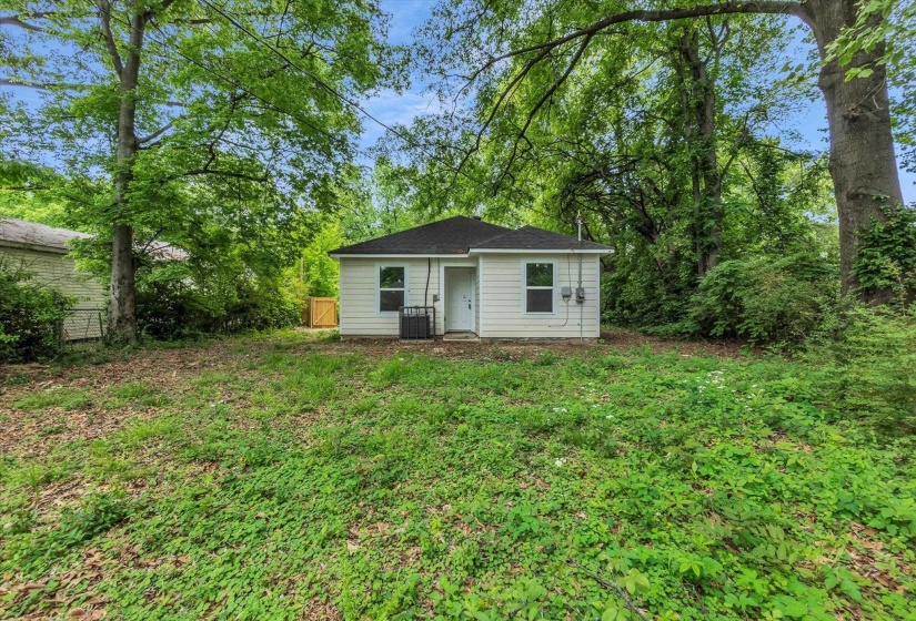 Rear exterior featuring white siding, a dark shingle roof, and a private back entrance