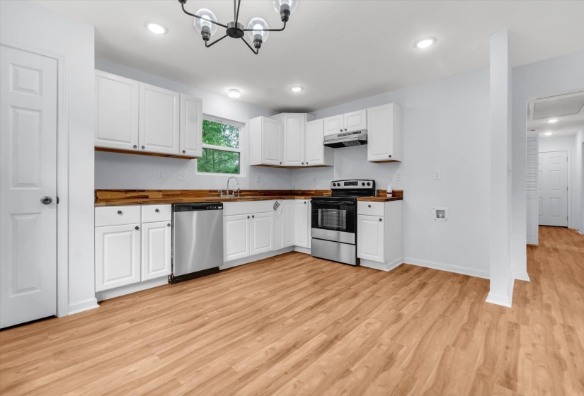 Kitchen featuring white cabinetry, wood-finish countertops, stainless steel appliances, and wood-finish flooring