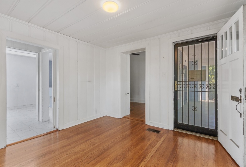 Interior space featuring rich wood-finish flooring, white paneled walls, and a white plank ceiling with a flush-mount light fixture