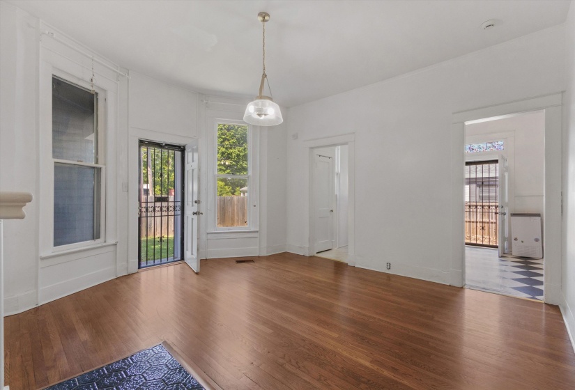 Open-concept room featuring wood-finish flooring, white walls, and a central pendant light fixture