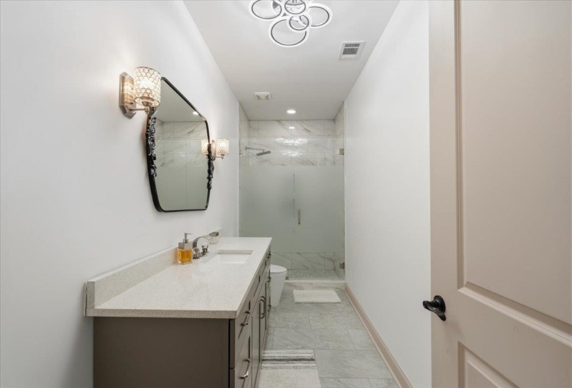 Contemporary bathroom featuring a double vanity with stone countertops, integrated sinks, and brushed nickel hardware