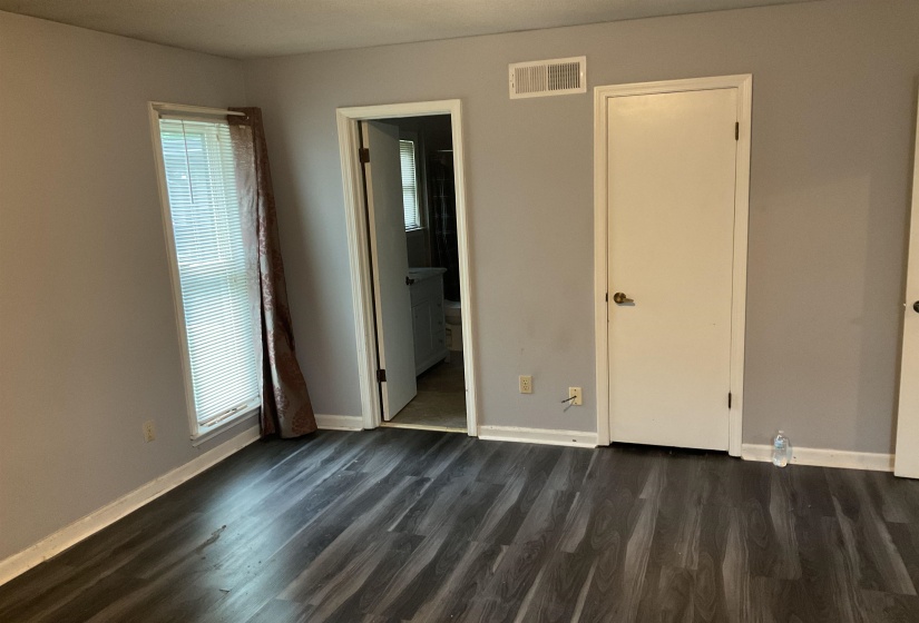 Dark wood-finish flooring with light gray walls, white trim, and a window with blinds