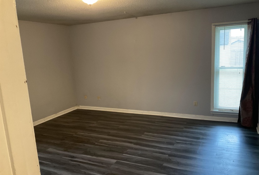 Room featuring wood-finish flooring, light gray walls, white baseboards, and a window with white trim