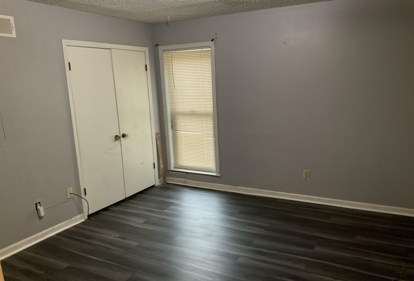 Interior space featuring dark wood-finish flooring, light grey painted walls, white trim, and a window with blinds