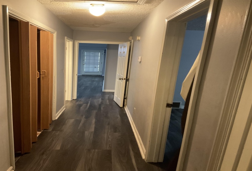 Hallway with dark wood-finish flooring, light grey painted walls, and white trim