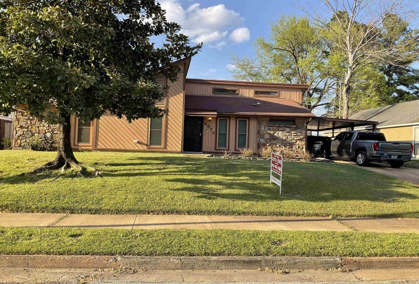 Mid-century inspired home featuring stone siding, an attached carport, and a front lawn