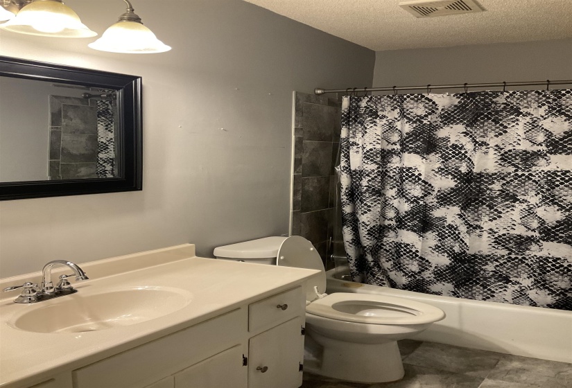 Full bathroom featuring a white vanity with integrated sink, chrome faucet, and framed mirror