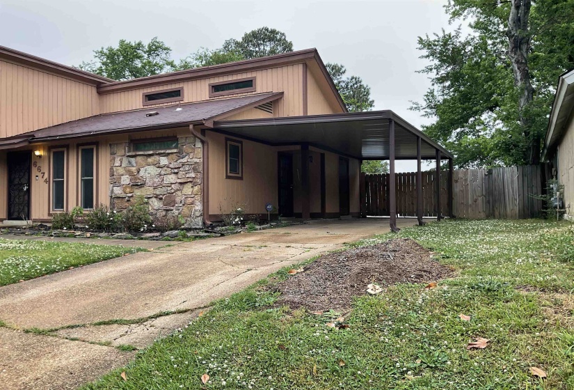 Property exterior featuring a stone facade accent, light brown siding, and a covered carport