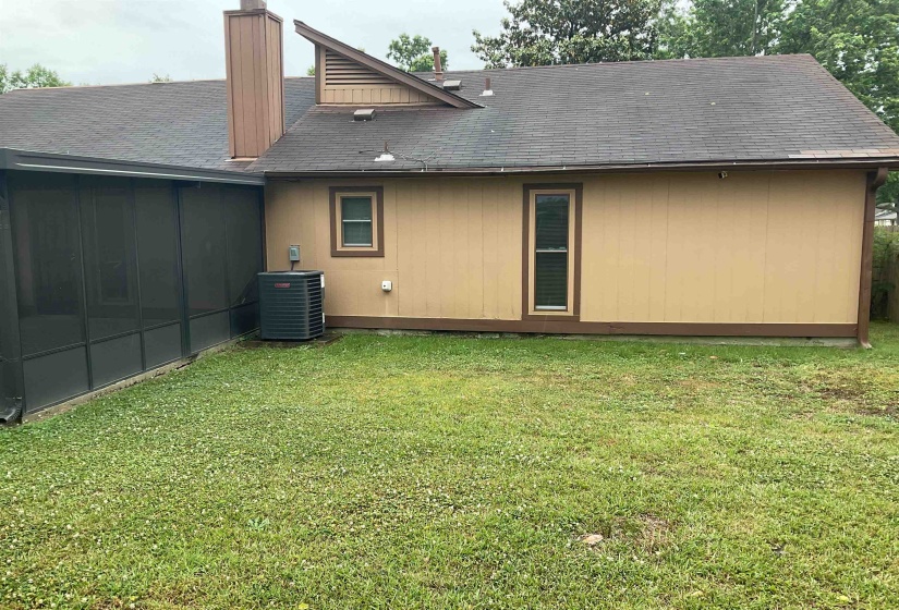 Expansive rear yard featuring a screened enclosure, a central air conditioning unit, and a durable asphalt shingle roof