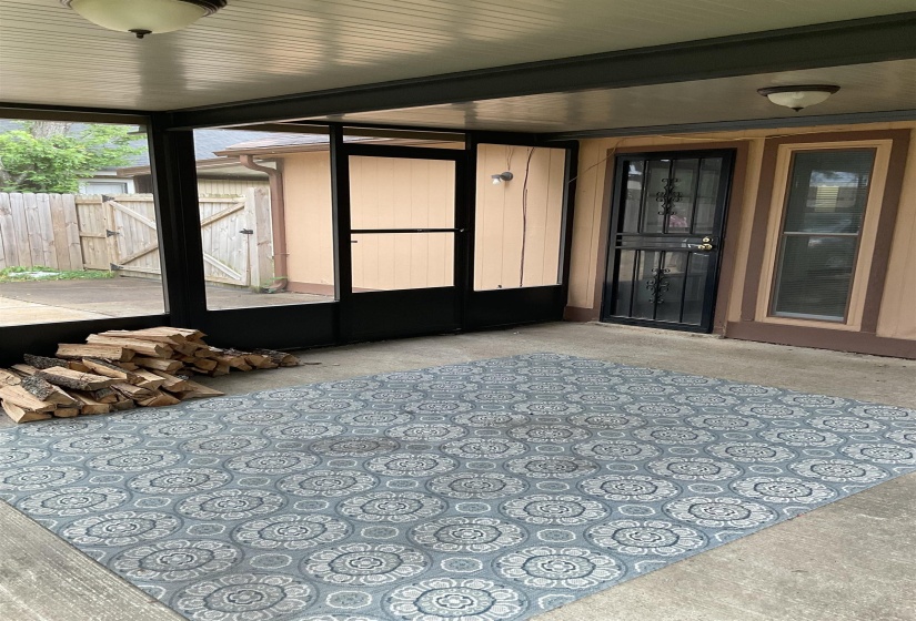 Screened-in patio featuring a concrete floor, overhead lighting fixtures, and a security screen door