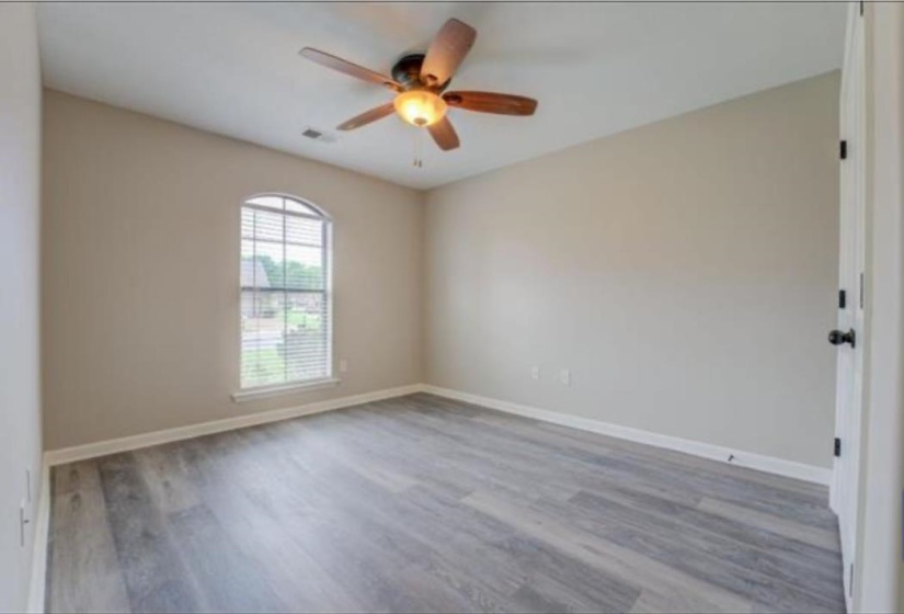 Room featuring light wood-finish flooring, an arched window with blinds, and neutral wall tones