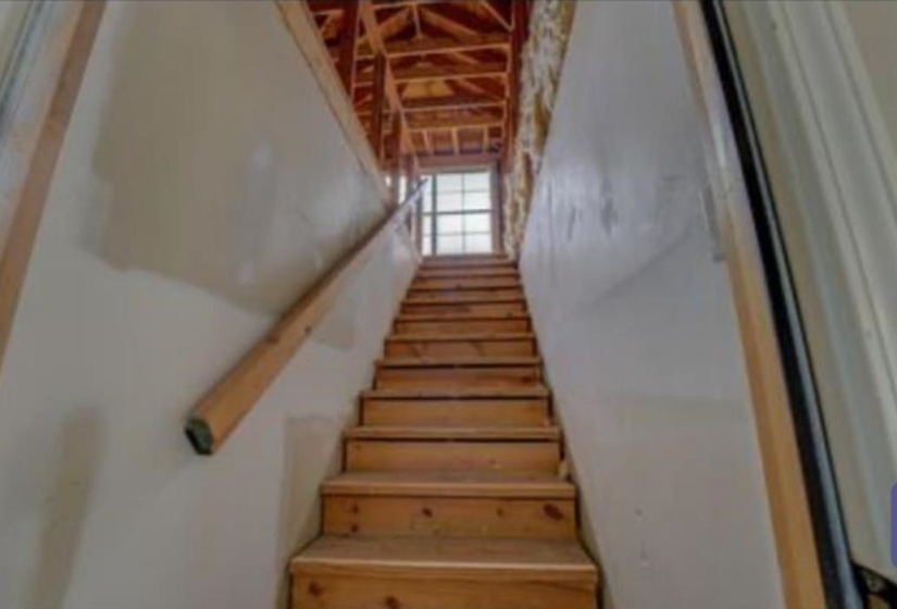 Wooden staircase with natural wood treads and risers, featuring a wood handrail