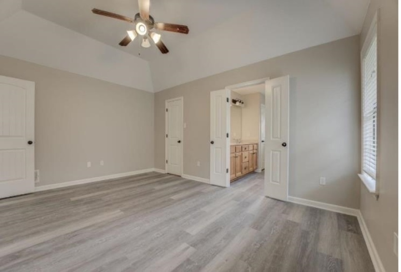 Spacious interior featuring wood-finish flooring, vaulted ceilings, and a ceiling fan