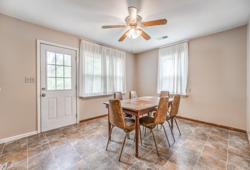 Versatile dining area featuring neutral wall tones, multi-tone tile flooring, and a ceiling fan with light fixture