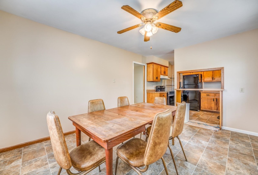 Dining area featuring a ceiling fan with light fixture, neutral wall paint, and tiled flooring