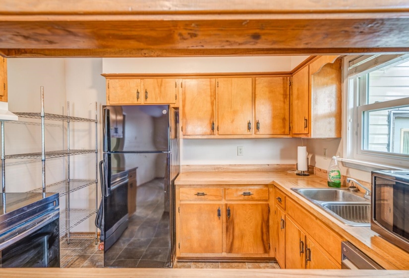 Kitchen featuring light wood cabinetry, a black refrigerator, and a stainless steel double-basin sink