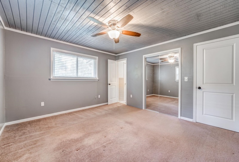 Room featuring gray walls, light brown carpet, and a wood-paneled ceiling