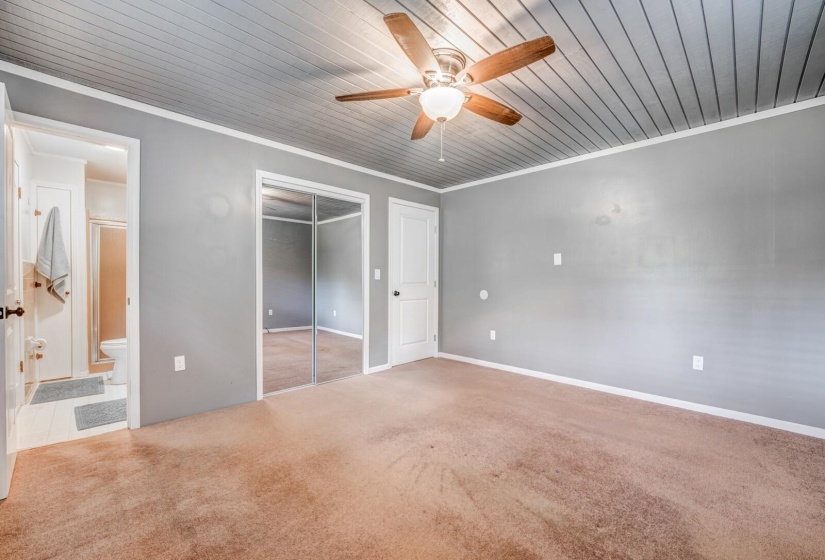 Spacious bedroom featuring neutral wall tones, textured ceiling, brown carpet flooring, and a ceiling fan with light fixture