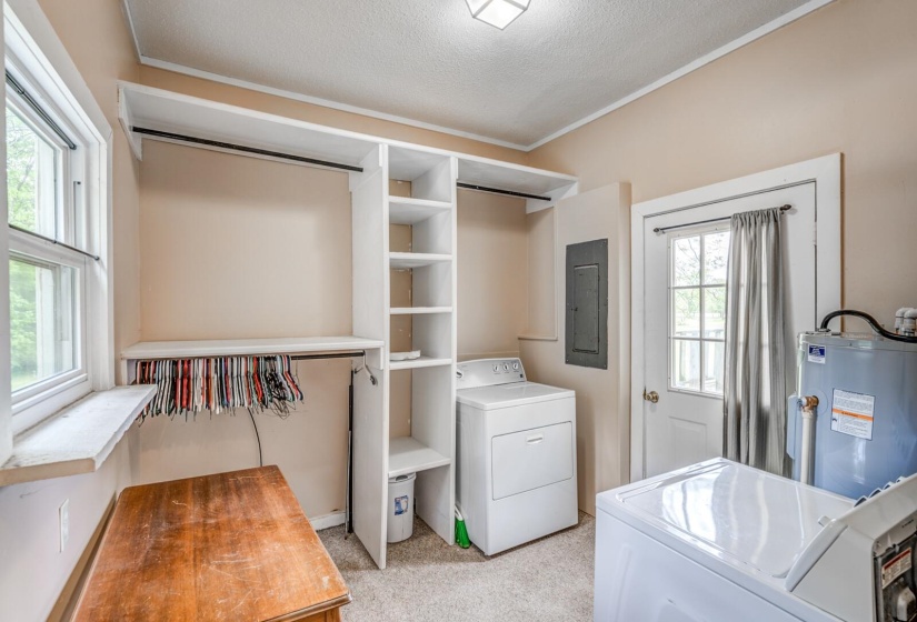 Dedicated utility area featuring a window, built-in shelving, hanging rods, and a white paneled door