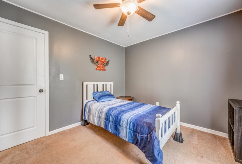 Neutral gray walls with white trim, brown carpet flooring, and a ceiling fan with integrated lighting