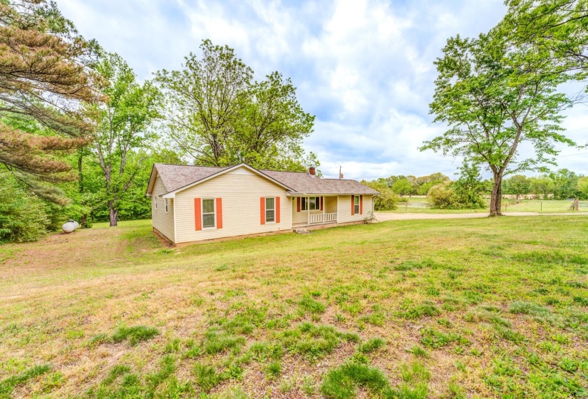 Single-story residence featuring light-colored siding, a covered front porch with white columns, and red decorative shutters