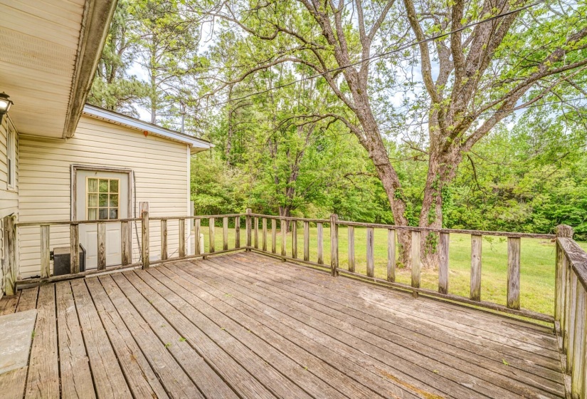 Spacious outdoor deck with natural wood railing overlooking a grassy expanse