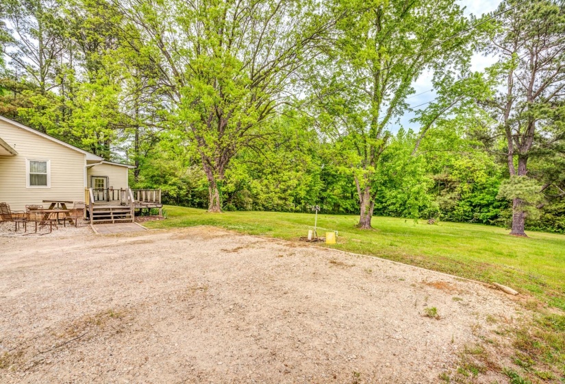 Spacious gravel driveway with a level grassy area and mature trees