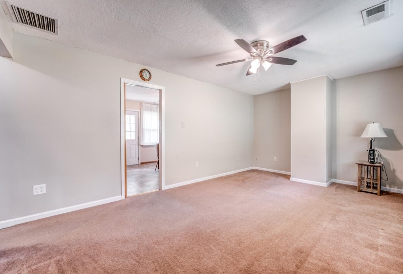 Carpeted room featuring a ceiling fan with integrated lighting, neutral wall paint, and white trim