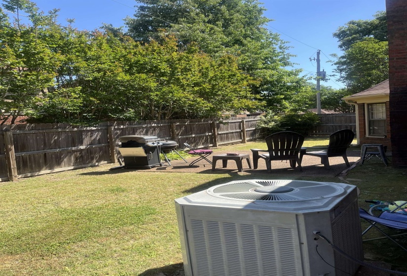 Enclosed backyard featuring a privacy fence, a concrete patio area, and mature perimeter trees