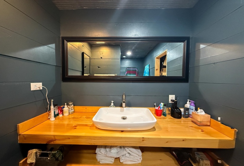 Bathroom vanity featuring a rectangular vessel sink, wood-finish countertop, and wall-mounted faucet