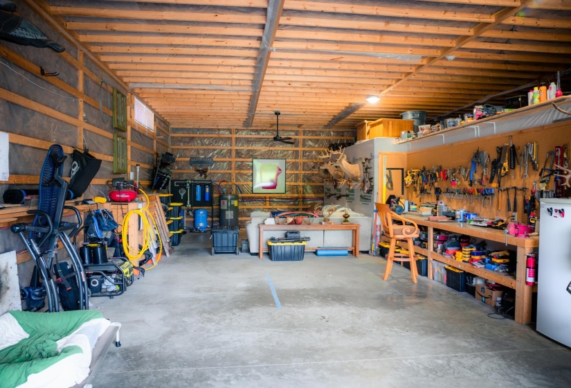 Spacious utility room featuring a concrete floor, exposed wood ceiling joists, and a ceiling fan