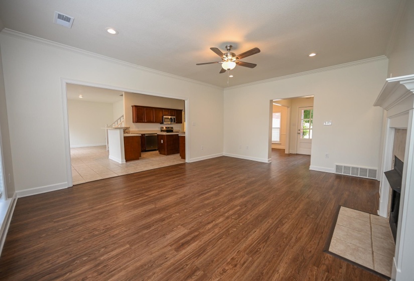 Expansive living area featuring wood-finish flooring, a ceiling fan with integrated lighting, and recessed ceiling lights