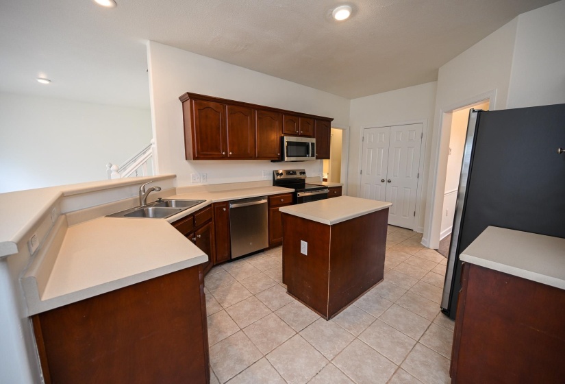 Kitchen featuring wood cabinetry, light-toned countertops, a stainless steel sink, and stainless steel appliances