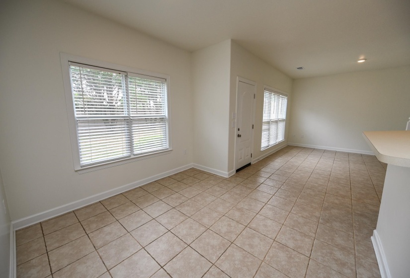 Spacious room featuring neutral-toned tile flooring, white baseboards, and light walls