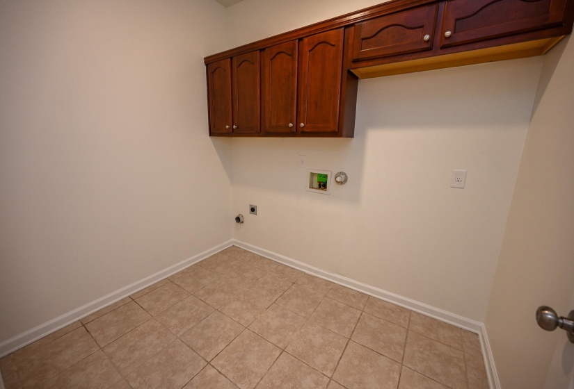 Laundry area featuring rich wood cabinetry, tile flooring, and utility hookups