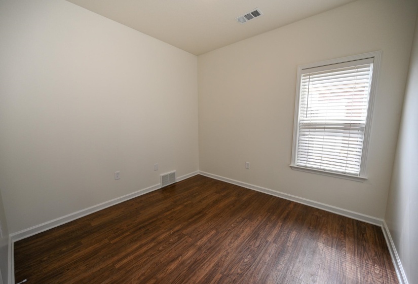 Room featuring wood-finish flooring, neutral wall tones, and white trim