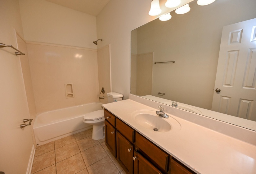 Bathroom featuring a built-in tub and shower combination with a tiled surround