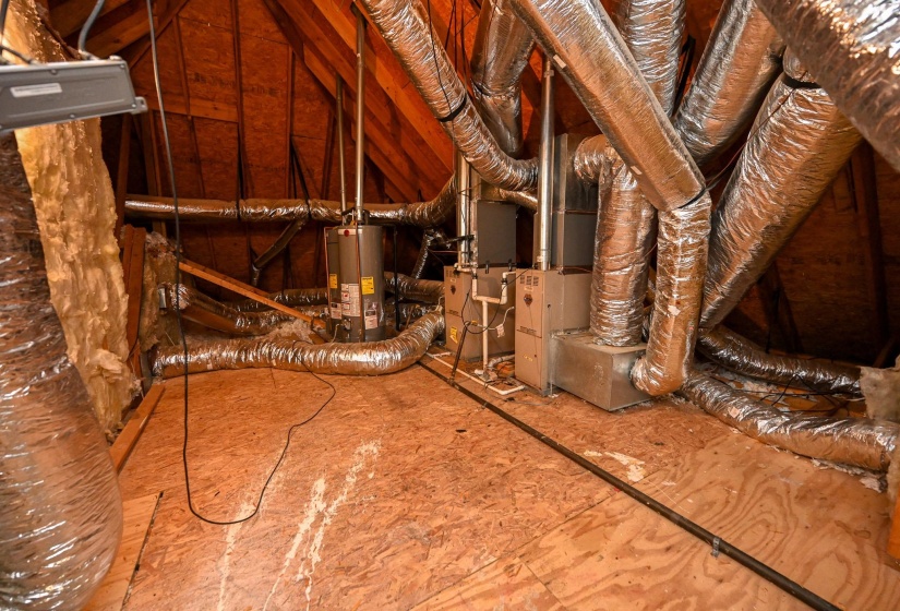 Attic space featuring exposed wood framing, insulated ductwork, and built-in mechanical systems