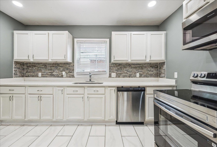Kitchen featuring white cabinetry, light countertops, and a mosaic tile backsplash